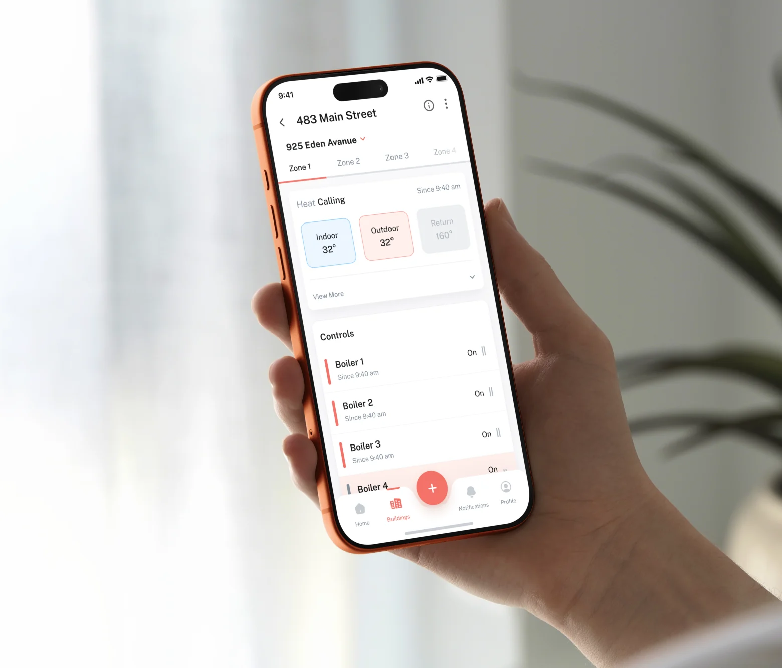 The Entech app held in one hand, showing a building at 483 Main Street: zone tabs, a Heat Calling status with indoor, outdoor and return temperatures, and a list of boilers each switched on.
